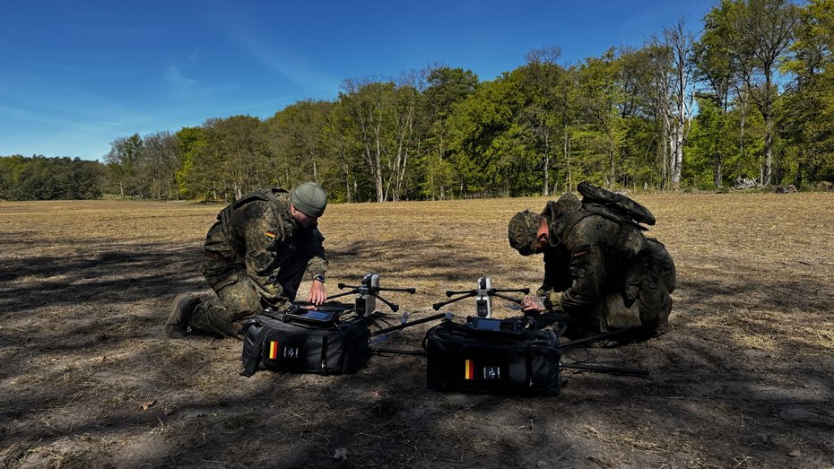 Zwei Einsatzkräfte bereiten AERIS Recon S7 Drohnensysteme mit mobilen Transporttaschen im Gelände für den Einsatz vor.